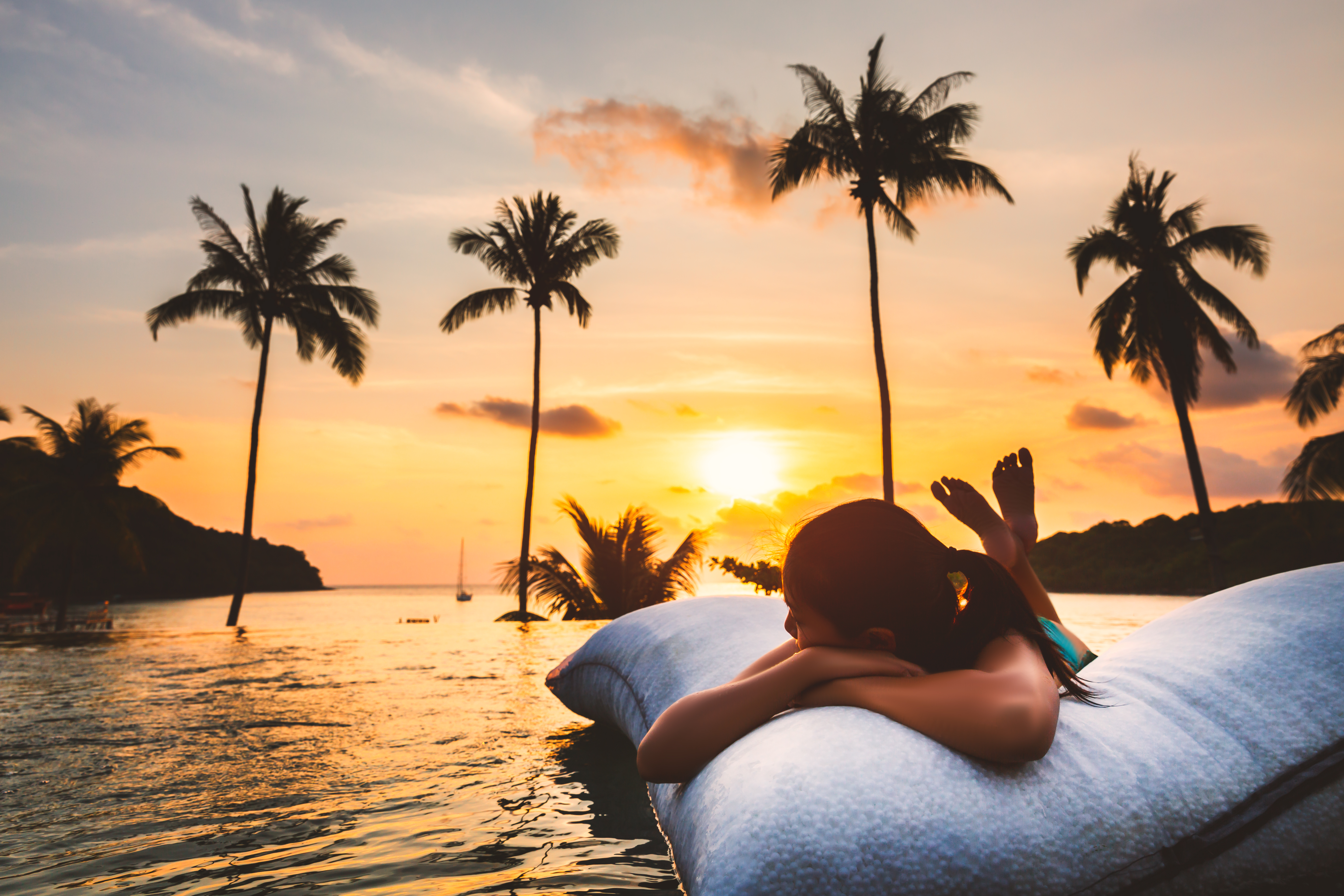 Woman with bikini relax in infinity pool hotel resort with sea beach and palm tree background at sunset in Koh Kood, Thailand