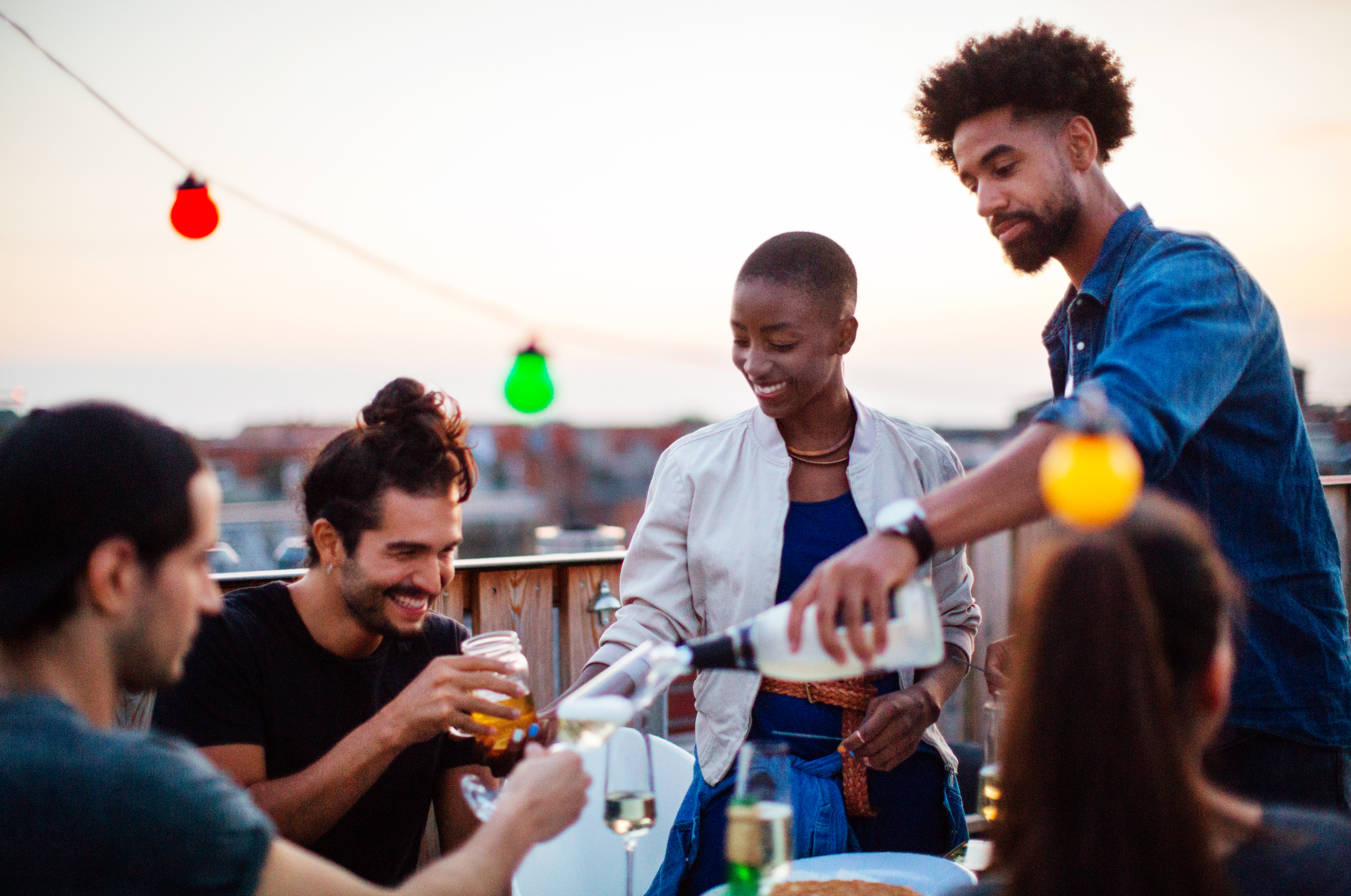 Adult friends getting together to enjoy dinner and drinks on a rooftop