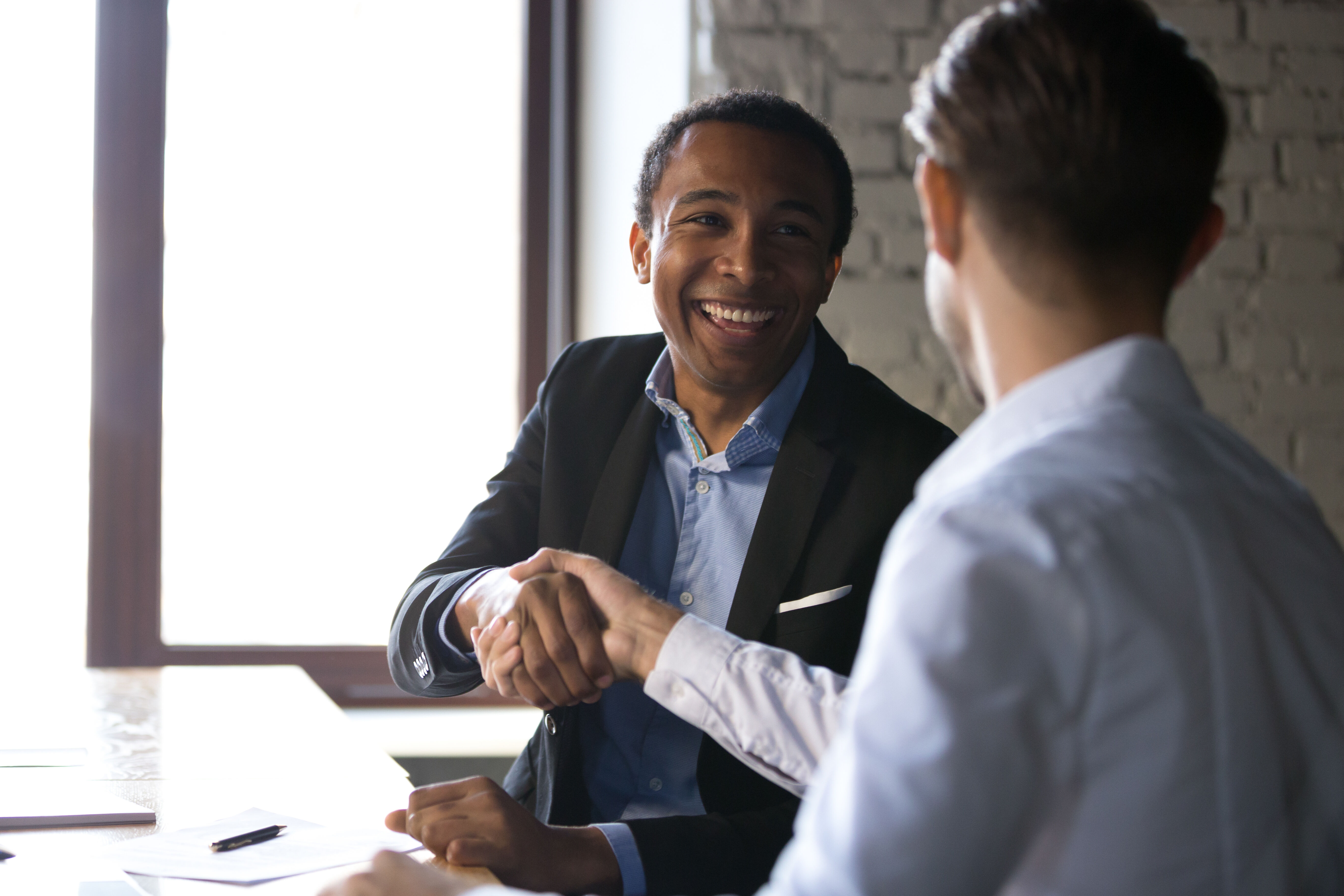 Satisfied black client shaking hands thanking manager for good deal